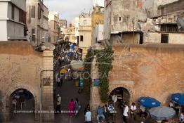 Image du Maroc Professionnelle de  Médina de Casablanca quelque soit l'angle choisi , des amas de caisses, d'objets ou de poubelles empestent ce lieu malgré qu'il fait partie du patrimoine historique de la Médina de Casablanca. El Bab E Jdid subit une dégradation due au vieillissement et à l’absence d’entretien, mais surtout au voisinage qui ne respect rien pour se protéger du soleil une bâche a été accroché à gauche avec du ciment sur la muraille de la ville au Boulevard Tahar El Aloui, ex (2e Tirailleurs). Par ailleurs les deux petites portes réservées aux passage des piétons sont devenue la propriété des cafés qui se situent de chaque côté de la porte dont on aperçoit quelques chaises, Vendredi 10 juillet 2009. (Photo / Abdeljalil Bounhar) 